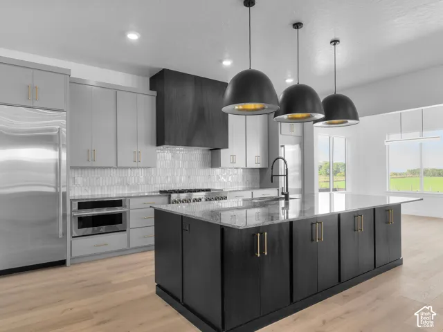 Kitchen featuring two-tone cabinetry, stone countertops, a large center island, matte black dome pendant lighting, and a vertical tile backsplash