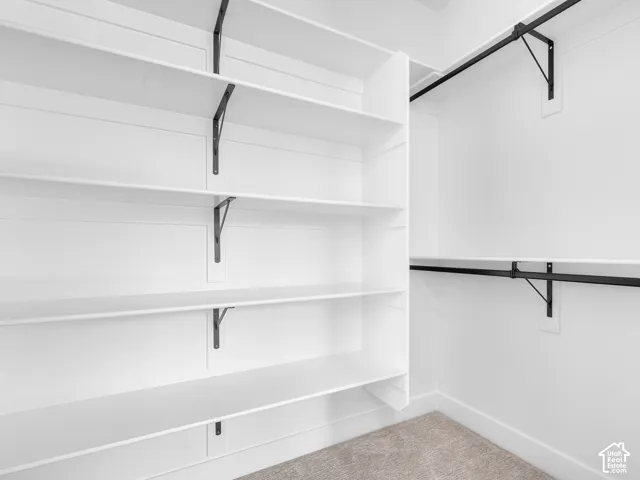 Custom walk-in closet featuring white built-in shelving, matte black metal support brackets, and two tiered hanging rods