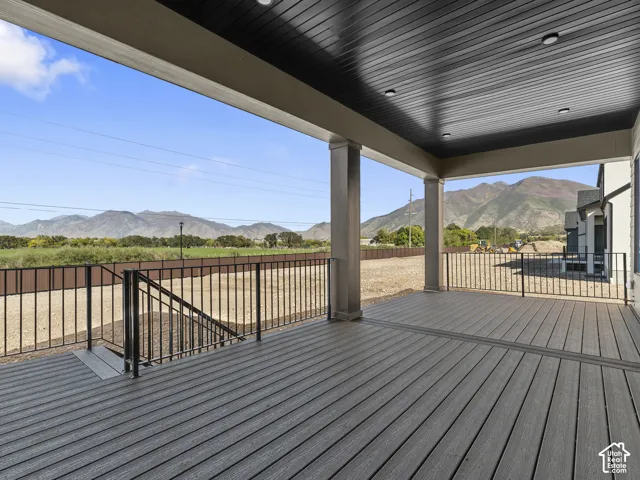 Covered outdoor deck featuring composite decking, black metal railing, recessed ceiling lighting, and mountain scenery