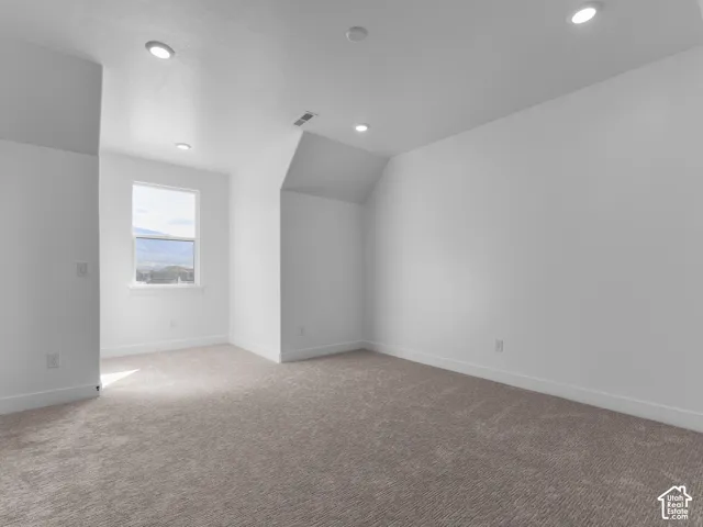 Neutral-toned carpeted flooring, recessed lighting, vaulted ceilings, and a single-pane window with mountain backdrop
