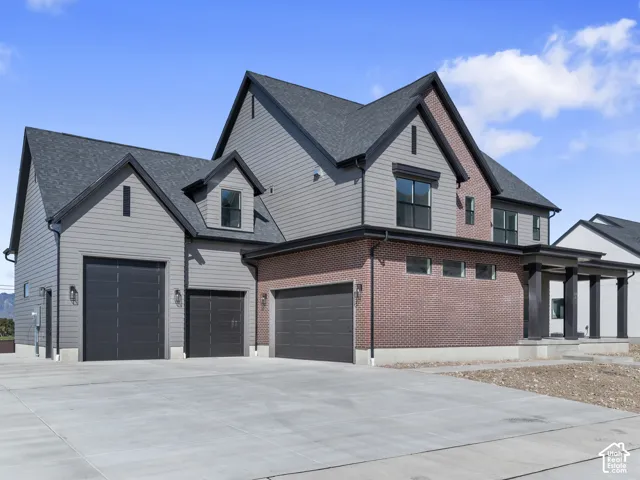 Multi-level exterior featuring a brick and horizontal siding facade, asphalt shingle roof, three-car garage configuration, and concrete driveway