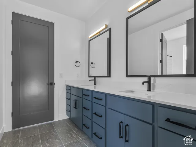Double vanity with a solid-surface countertop, dual undermount sinks, matte black fixtures, framed rectangular mirrors, and charcoal-toned cabinetry