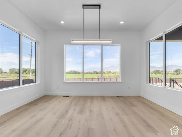 Light-filled interior featuring wood-finish flooring, extensive floor-to-ceiling windows, mountain scenery, and a minimalist linear pendant light fixture