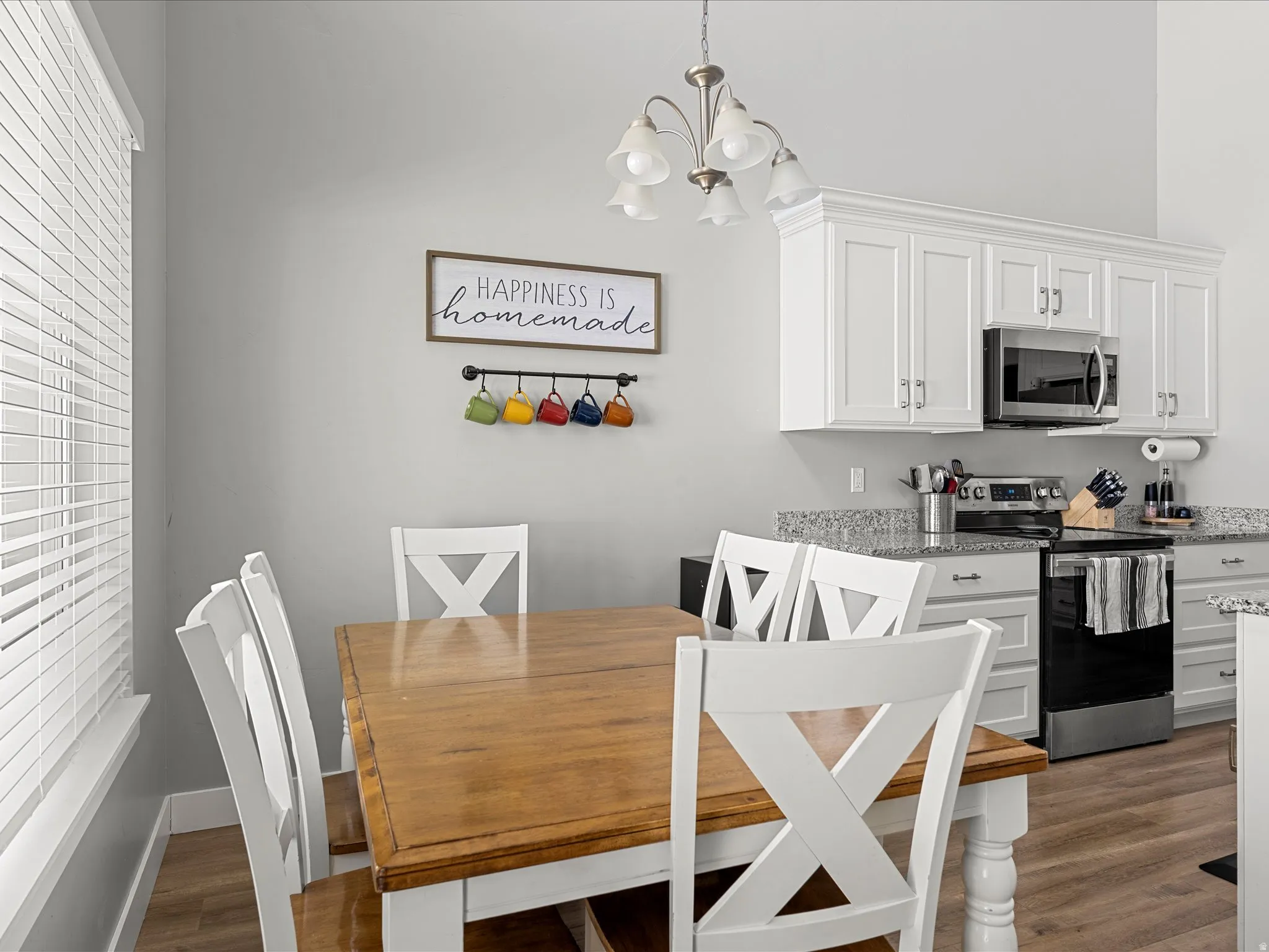 Dining area featuring a wood-finish table, white X-back chairs, and a contemporary chandelier