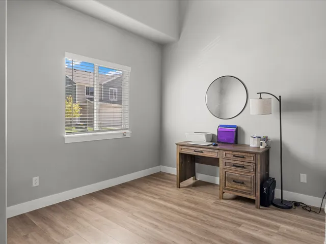 Bright room featuring wood-finish flooring, a window with white blinds, and light gray walls