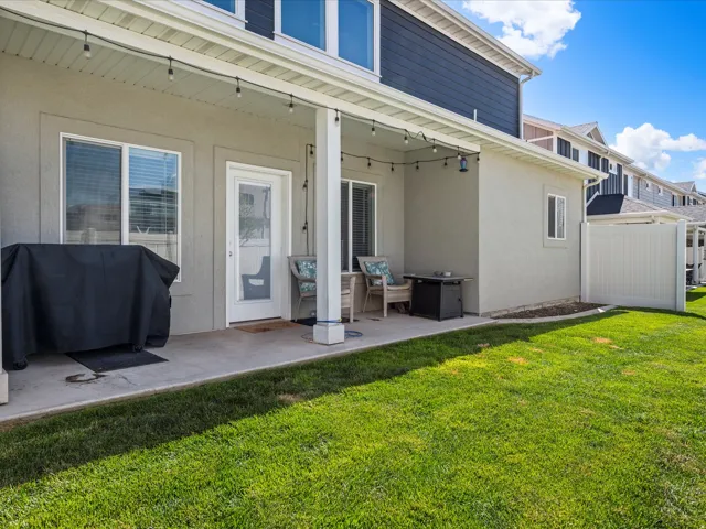 Covered concrete patio with recessed lighting and string lights, featuring a private fenced yard and stucco exterior