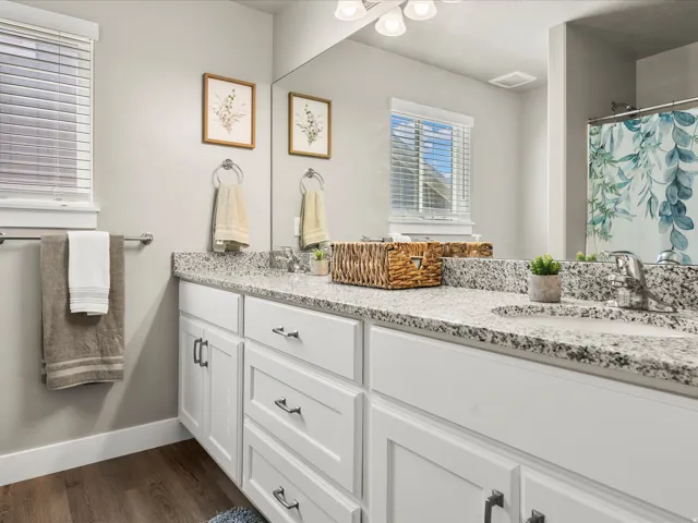 Bathroom featuring a double vanity with stone countertops, white shaker cabinetry, and integrated sinks