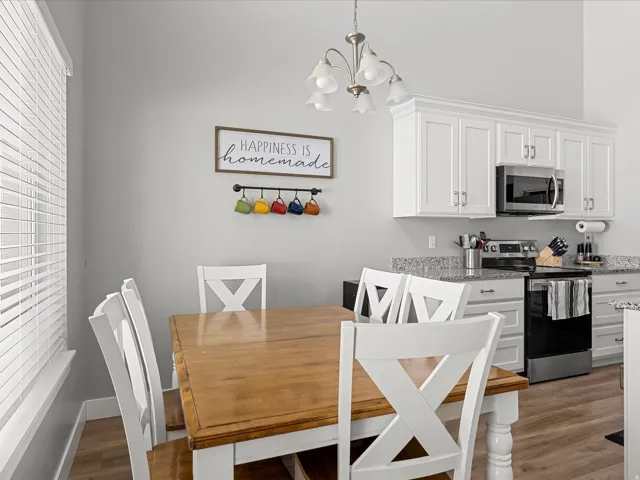 Dining area featuring a wood-finish table, white X-back chairs, and a contemporary chandelier