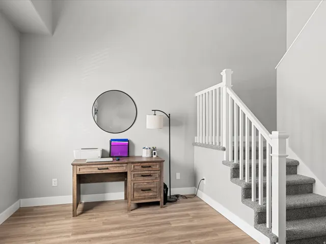 Open-concept area featuring light wood-finish flooring, white baseboards, and a carpeted staircase with white balusters