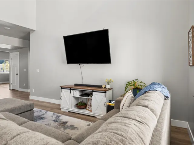 Living area featuring light gray wall tones, wood-finish flooring, and white baseboards