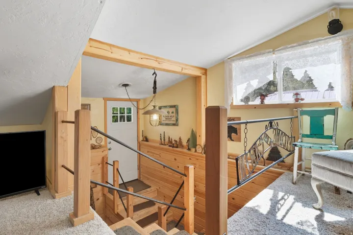 Upper level landing featuring wood-paneled walls, a window with natural light, and a white door with multiple glass panes