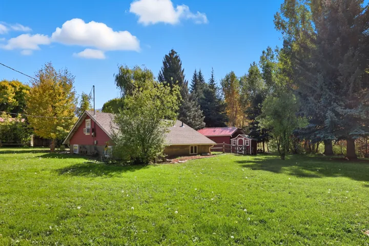 Expansive green lawn surrounds a red-sided structure with a brown roof