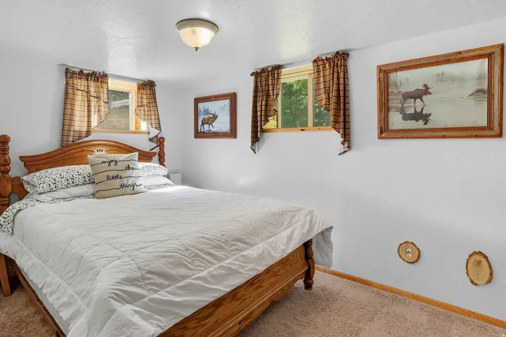 Carpeted bedroom with white walls and a wood-finish bed frame