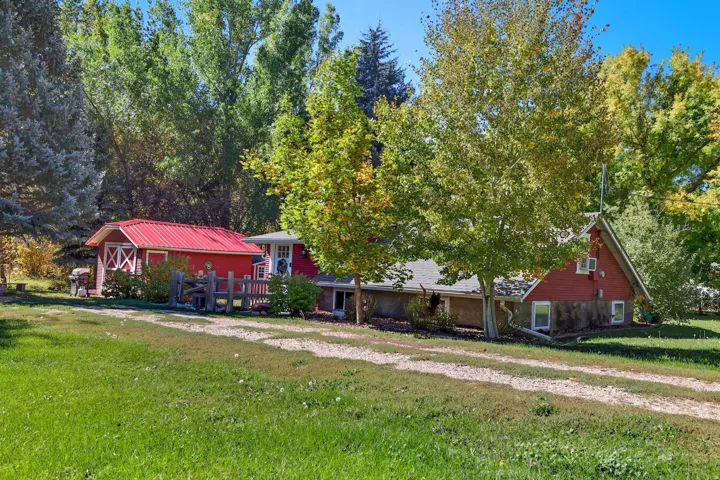 Red-painted outbuilding with a metal roof and cross-brace detailing