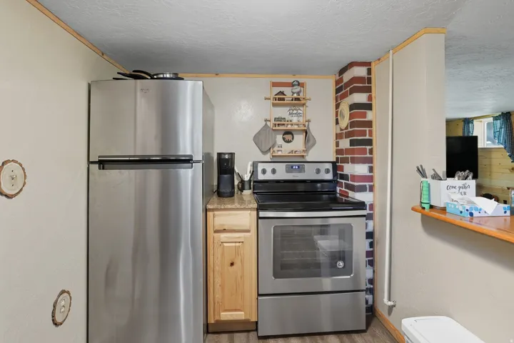 Kitchen area featuring stainless steel appliances, including a top-freezer refrigerator and a range with a black cooktop