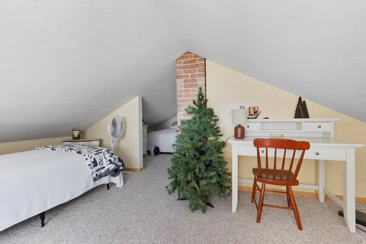 Carpeted room featuring a sloped ceiling, exposed brick detail, and painted walls