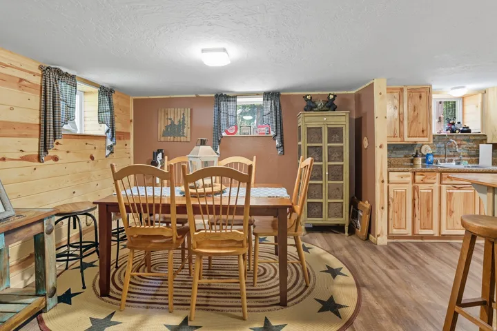 Dining area with wood-finish flooring, featuring a rectangular wood table with chairs, and natural wood paneling on one wall