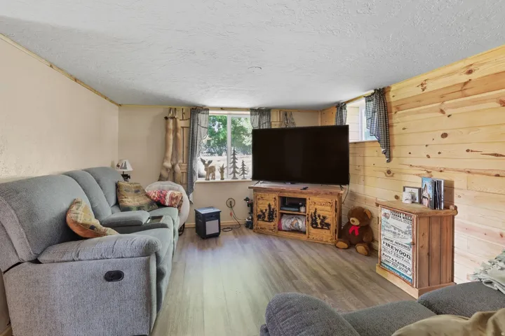 Living area featuring a wood-finish flooring, a paneled accent wall, and a window providing natural light