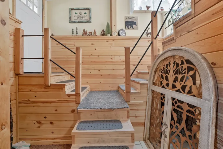 Natural wood plank walls and staircase featuring carpeted treads and black metal railings