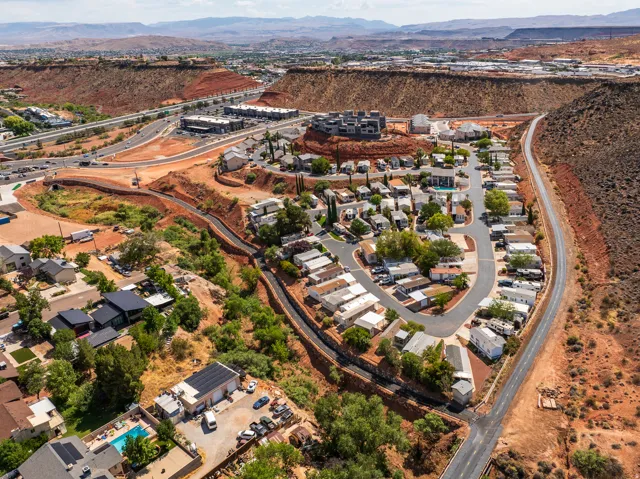 Aerial perspective showcasing a residential community nestled within a landscape of red rock formations and natural vegetation