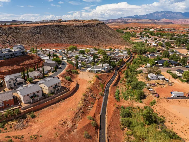 Residential area nestled within a red rock landscape, featuring a paved pathway