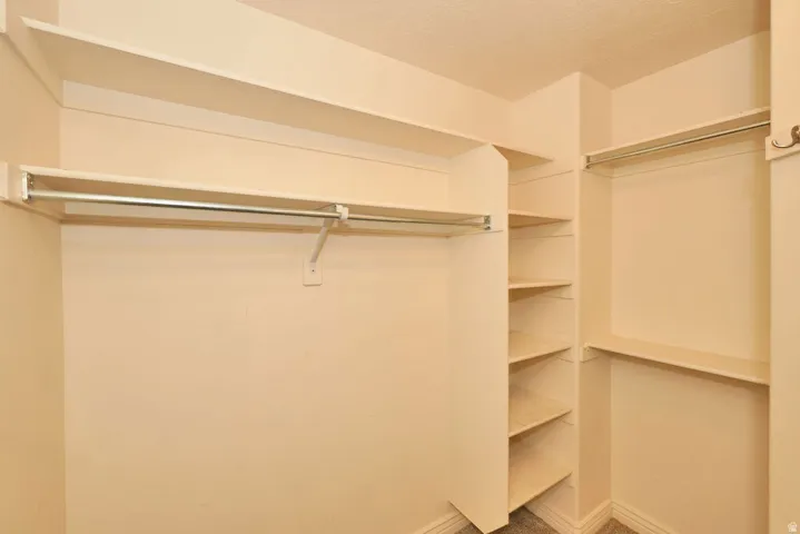 Walk-in closet featuring extensive built-in shelving, multiple hanging rods, and neutral-toned walls