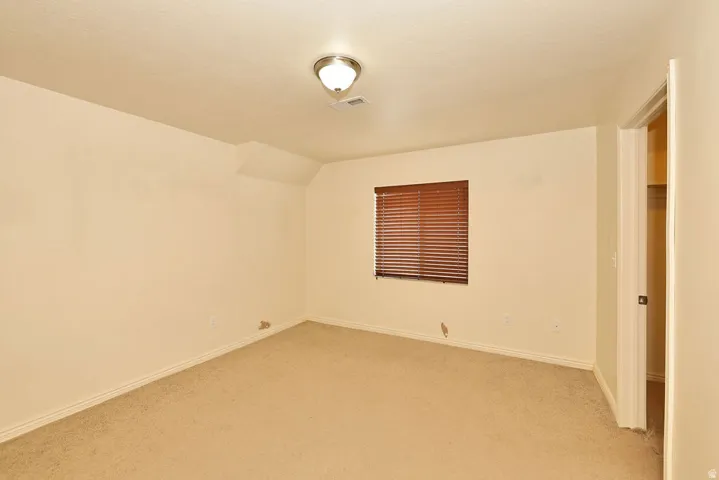 Neutral-toned carpeting and walls complement the window with brown horizontal blinds