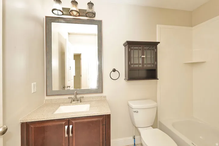 Bathroom featuring a wood-finish vanity with a light-toned countertop, a rectangular sink, and a brushed nickel faucet