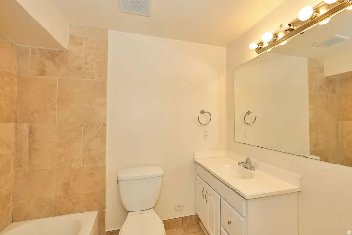 Bathroom featuring a white vanity with integrated sink, a large wall-mounted mirror, and a multi-bulb light fixture