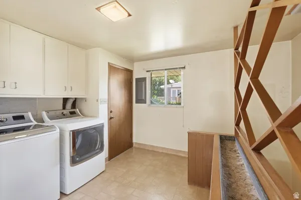 Utility room featuring extensive upper cabinetry, a single window, a solid-core door, and a decorative wooden screen