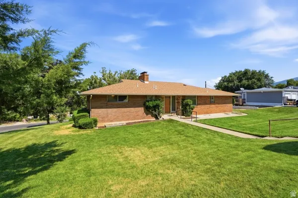 Brick ranch-style residence featuring a brown shingle roof and a front entry