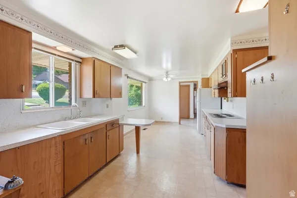 Kitchen featuring wood-finish cabinetry, white countertops, and a double basin sink