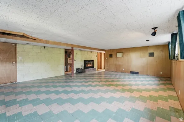 Spacious room featuring patterned floor tiles, a built-in fireplace, paneled walls, and a drop ceiling