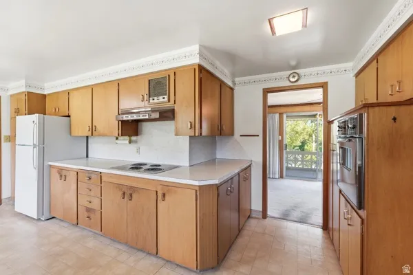 Kitchen featuring wood-finish cabinetry, built-in wall oven, and tile flooring