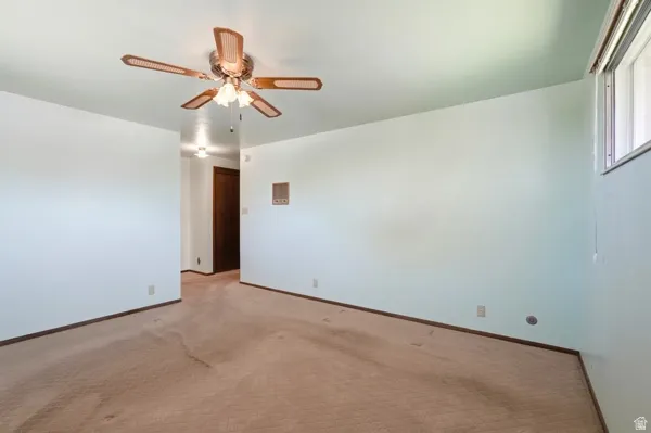Living area featuring a ceiling fan with light fixture, light-toned walls, and a window providing natural light