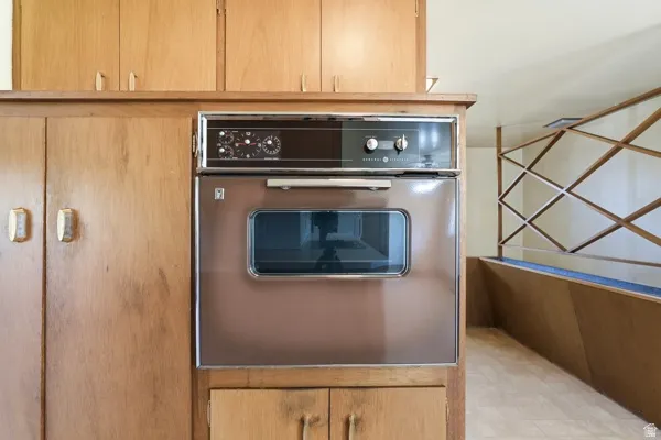 Built-in wall oven with wood-finish cabinetry, showcasing a distinctive decorative room divider and light-colored flooring