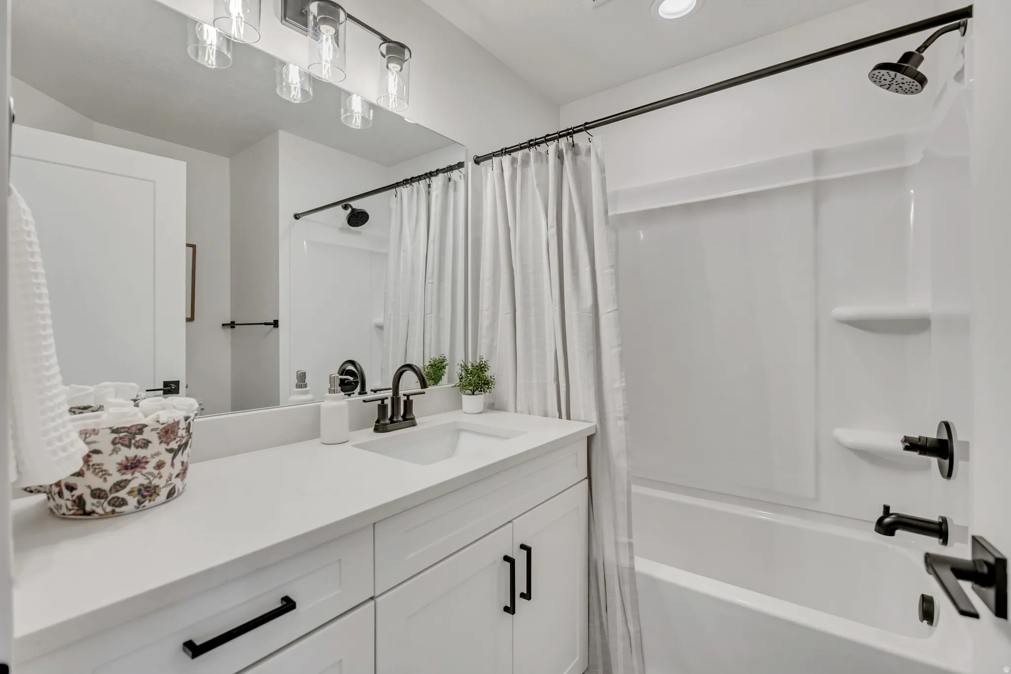 Bathroom featuring a white vanity with integrated sink, matte black fixtures, and overhead task lighting