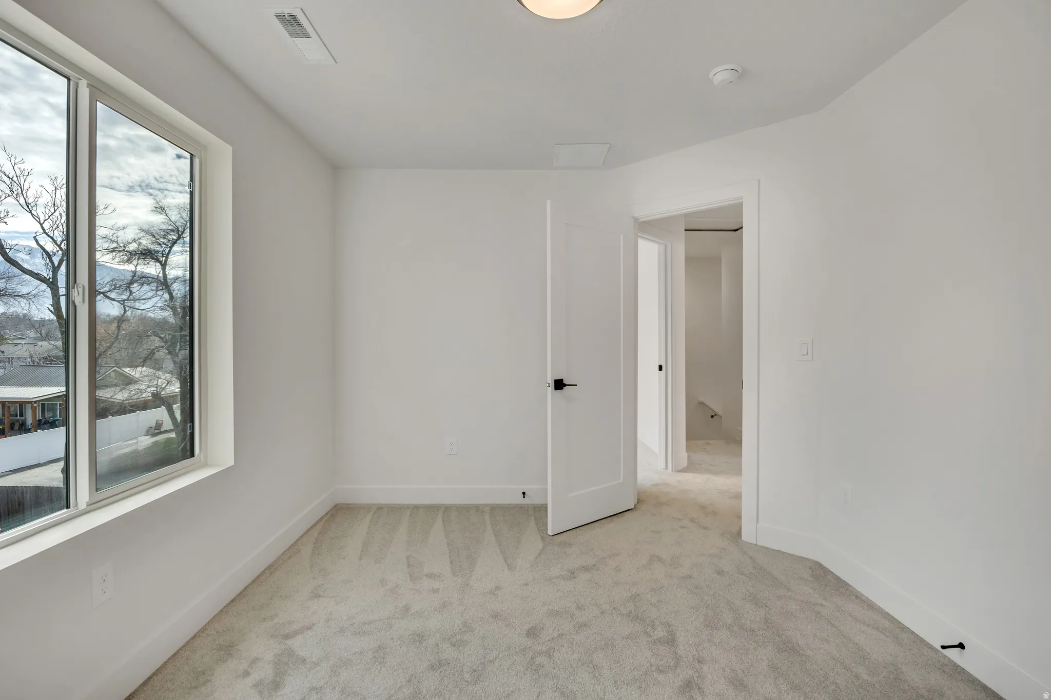 Bright room with light gray carpet, white walls, and a large window