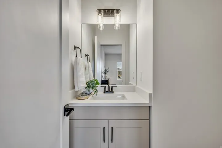 Bathroom vanity featuring a light gray cabinet, white countertop, rectangular undermount sink, matte black faucet, and coordinating towel ring