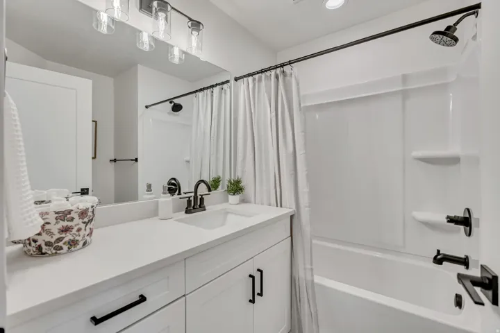 Bathroom featuring a white vanity with integrated sink, matte black fixtures, and overhead task lighting