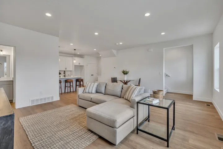 Open-concept living space featuring wood-finish flooring, recessed lighting, and a white color palette