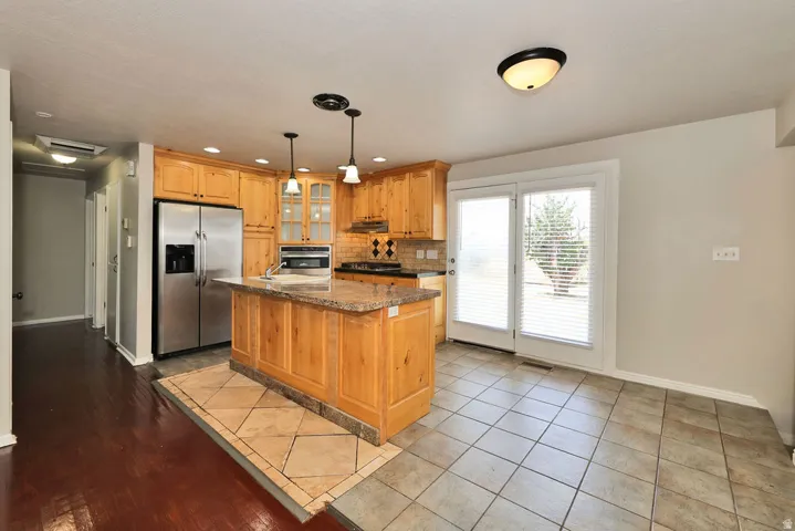 Kitchen featuring wood cabinetry, stainless steel appliances, and a central island with a stone-finish countertop