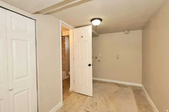 Utility area featuring a ceiling-mounted light fixture, visible plumbing hookups, and light beige wall paint