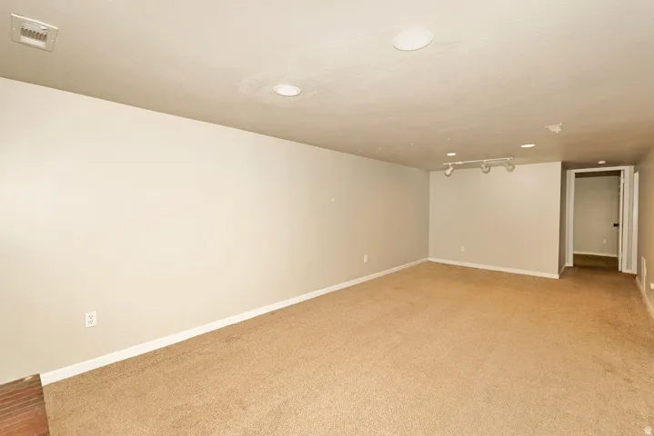 Expansive room featuring neutral-toned carpet, recessed lighting, and track lighting fixtures