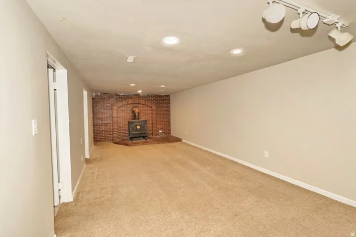 Spacious room featuring a brick fireplace with an arched opening, a wood-burning stove, and a raised hearth