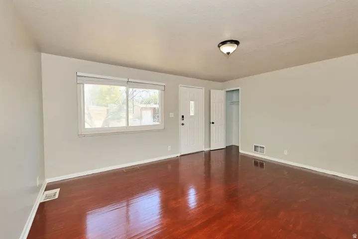 Expansive room featuring rich wood-finish flooring, light-toned walls, and a multi-pane window