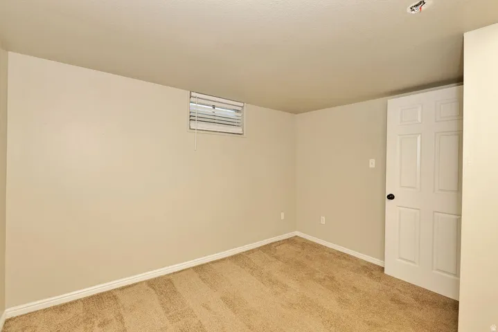 Carpeted room with neutral wall tones and a white six-panel door