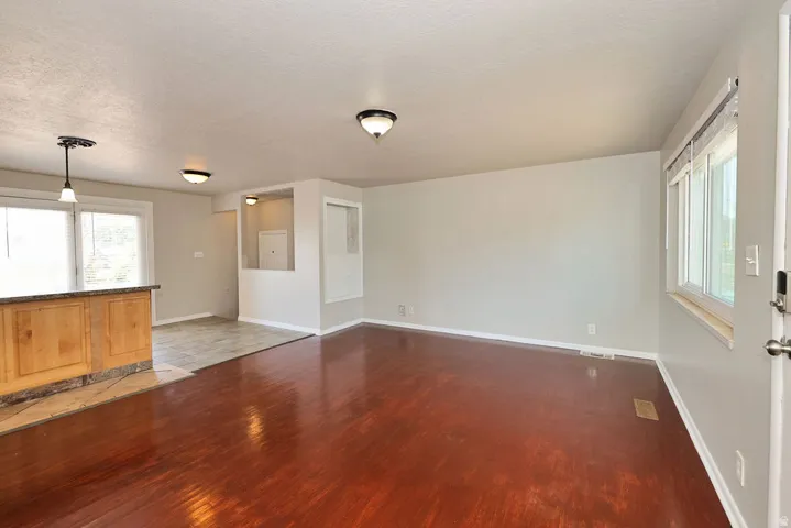 Spacious interior with wood-finish flooring, light neutral wall colors, and a large window providing natural light