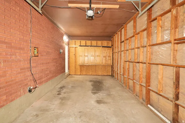 Spacious garage featuring a concrete floor, exposed brick wall, and built-in wood cabinetry