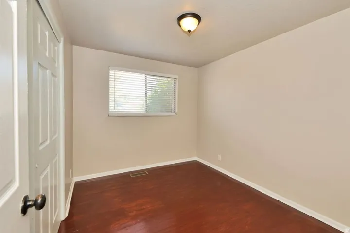 Room featuring rich wood-finish flooring, neutral wall paint, and white trim throughout